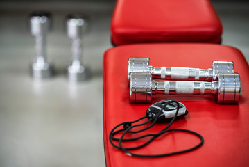 Pair of silver dumbbells and stopwatch in gym