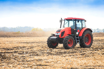 Modern red tractor in the field.