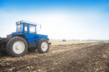 Old blue tractor in a empty field. Agricultural machinery, field work.