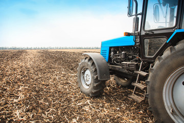 Obraz premium Old blue tractor in a empty field. Agricultural machinery, field work.
