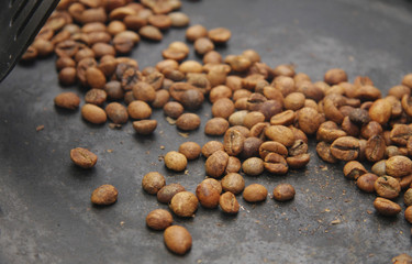 Green coffee beans roasting on the black pan