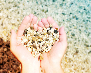 Heart from sea a pebble in female hands. 