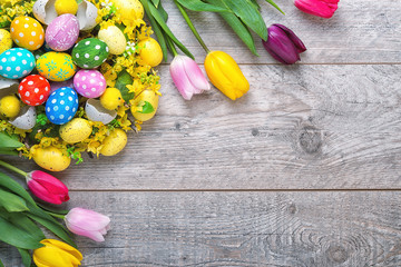 Easter eggs  and colorful tulips on wooden background.Easter holiday concept.	