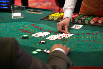 Dealer puts down a card on blackjack table - obrazy, fototapety, plakaty