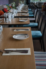 Glasses, flower fork, knife served for dinner in restaurant with cozy interior