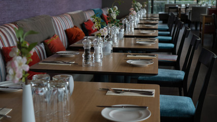 Glasses, flower fork, knife served for dinner in restaurant with cozy interior