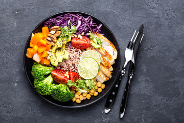 Buddha bowl dish with chicken fillet, brown rice, avocado, pepper, tomato, broccoli, red cabbage,...
