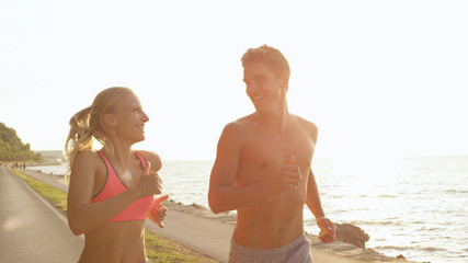 CLOSE UP: Happy boy and girl look in each other's eyes during fun seaside jog.