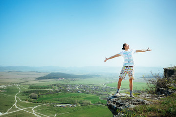 Photo of young handsome serious man standing over mountains and looking aside