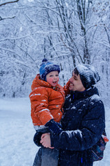 Fototapeta premium Father and his son playing outside, winter forest on the background, snowing, happy and joyful