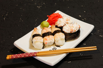 Nigiri Sushi set on white plate on black background. Japanese food. Asian tasty dinner.