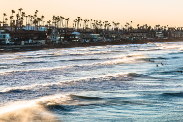 Surfers at dawn amid crashing waves in Oceanside, California, located in San Diego County.