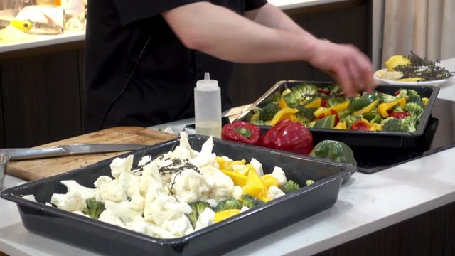 Chef mixes vegetables for cooking. Broccoli, cauliflower and pepper marinated in a tray on the table. HD video