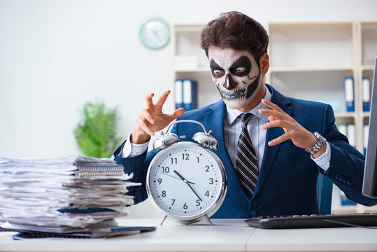 Businessmsn with scary face mask working in office