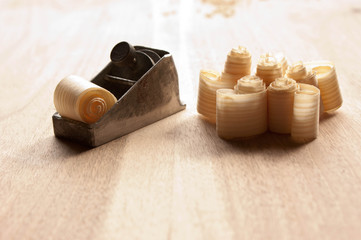 Small plane on a wooden background with shavings