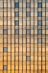 Side of a glass tower building with sky and sun reflecting on its surface
