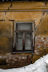 Shabby grungy cracked wall, broken windows, abandoned house, winter, poverty concept 
