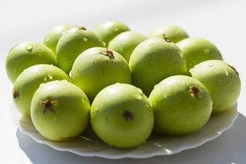 Fourteen fresh, green, pears, delicious fruit, on a white plate in the sunlight; 