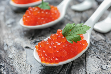 Spoons with delicious red caviar on table, closeup