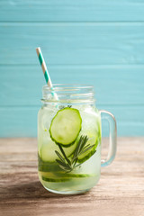 Mason jar of fresh lemonade with cucumber on wooden table
