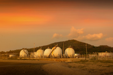 Spherical  storage tank storing liquefied gas and chemical liquids on sunset sky.