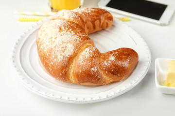 Plate with fresh tasty crescent roll on white table