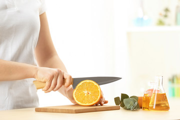 Woman preparing citrus perfume oil at table indoors
