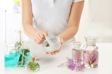 Obraz na płótnie Canvas Woman preparing perfume oil at table indoors