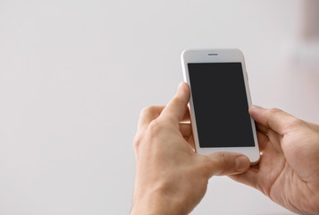 Man holding smartphone with blank screen on blurred background