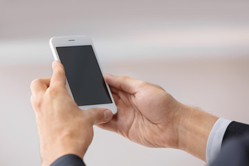 Man holding smartphone with blank screen on blurred background
