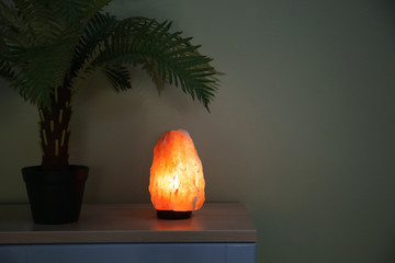 Himalayan salt lamp on wooden cabinet. Interior design element
