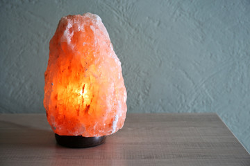 Himalayan salt lamp on table against light background