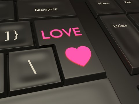 Pink love and heart button on a black keyboard. Quick access to internet online dating.