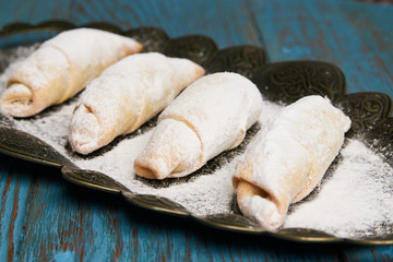 Mutaki cookies rolled with powdered sugar on copper tray on rustic wooden table, turkish food 