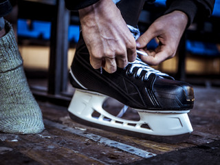 close up shot of hand tie shoelaces of ice hockey skates in locker room