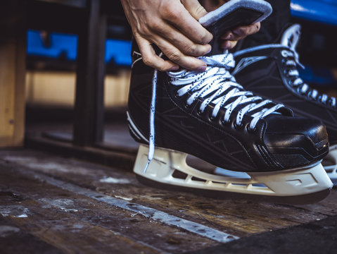 close up shot of hand tie shoelaces of ice hockey skates in locker room