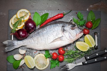 Fresh Dorado fish with spices and vegetables on slate plate