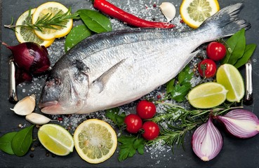 Fresh Dorado fish with spices and vegetables on slate plate