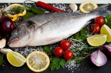 Fresh Dorado fish with spices and vegetables on slate plate