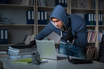 Young hacker hacking into computer at night
