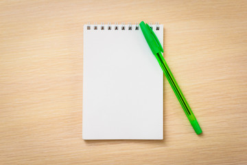 Green pen with notebook on wooden table