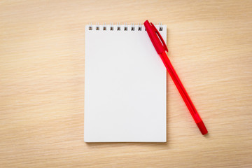  Red pen with notebook on wooden table