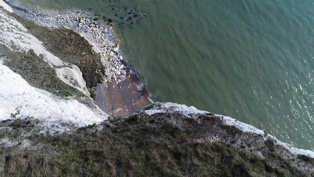 Aerial top down view flight over White Cliffs of Dover edge looking down showing rocky shore and ocean these are cliffs that form part of the English coastline facing the Strait of Dover and France 4k