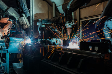 Team robots welding movement assembly automotive part in car factory. 