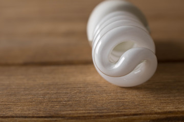 Energy-saving light bulb lies on a wooden table
