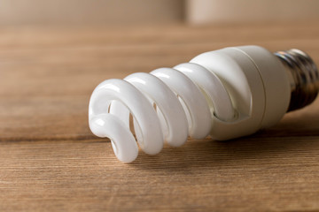 Energy-saving light bulb lies on a wooden table