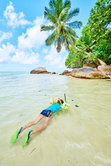 a little boy with mask and snorkel in the water in tropical beac
