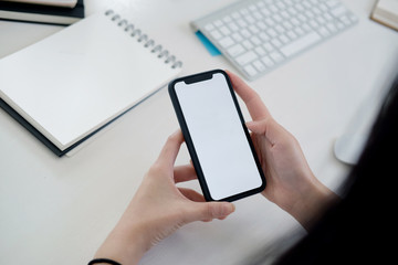 Woman texting on smart phone on desk in office.