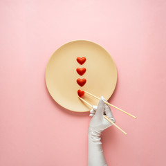 Dinner is served / Creative concept photo of kitchenware with hand, painted plate with food on it on pink background.