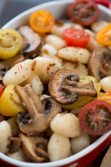 Close-up of boiled potato gnocchi with roasted mushrooms and fresh sliced tomatoes, selective focus